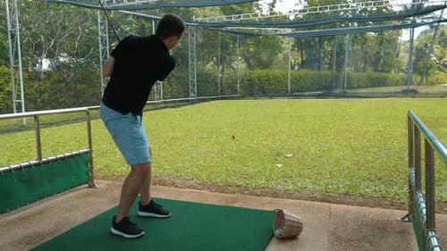 Man Golfing on Tropical Outdoor Driving Range