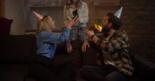 Une fille blonde donne des verres de boissons à ses amis, ils font ensuite tinter des verres lors d'une fête à la maison