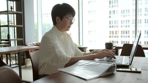 Attraktive reife Geschäftsfrau, die im Büro oder Coworking am Laptop arbeitet