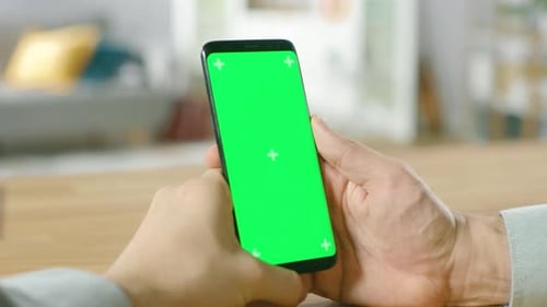 Close-up of a Man Uses Green Mock-up Screen Smartphone and Does Touchscreen Gestures. Touching Mobi