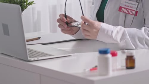 Doctor Works at Desk with Laptop and Medicine