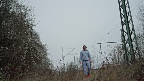 Person Advances On Grassy Train Embankment Scene Man Strides Across Railway Embankment Beneath