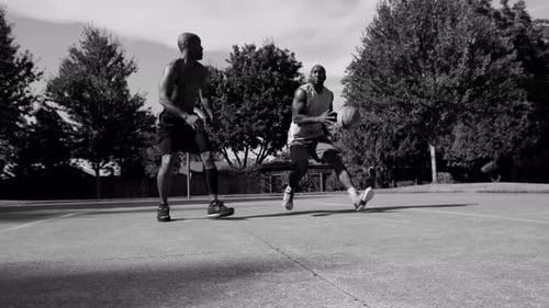 Intense one on one street basketball game in an urban park with african american athlete