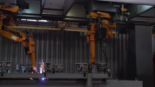 Braços robóticos realizando operações de soldagem em ambiente industrial