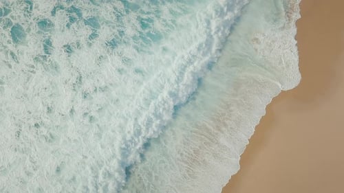 Powerful ocean waves breaking at the coastline, creating white foam and abstract water patterns.