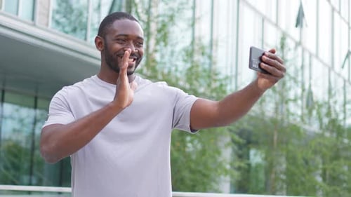 African American Man Holding Smartphone Having Video Chat on Urban Street in City Guy Blogger