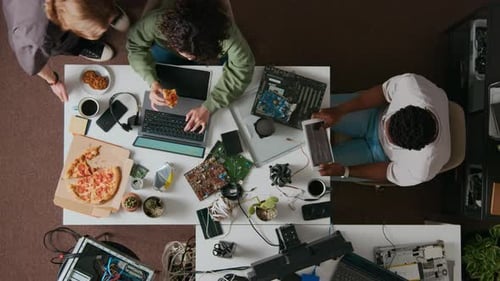 People Working at Table Eating Pizza Overhead View