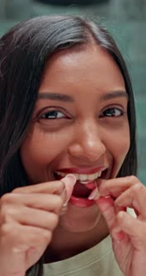 Young Woman Flossing Teeth in Bathroom