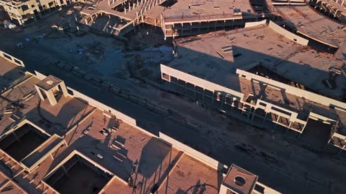 Zumbido aéreo sobre los tejados de un complejo de concreto sin terminar al atardecer de la Hora Dorada