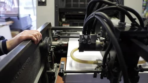 Industrial printer uploads white sheets of paper, close up