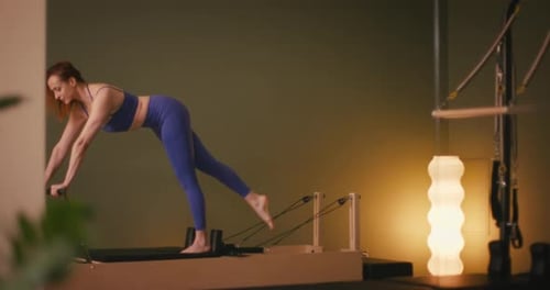 Woman Performs Pilates Exercise on Reformer Machine