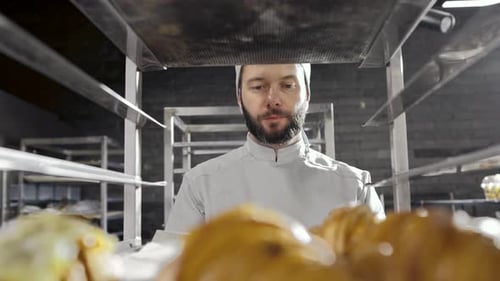 Baker Placing Fresh Croissants on Metal Rack