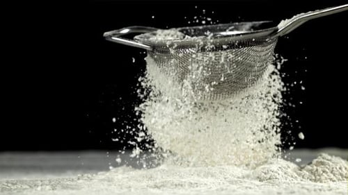 The Flour is Sifted Through a Sieve On a Black Background Filmed on a Highspeed Camera at 1000 Fps