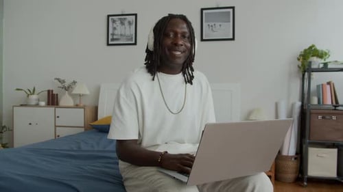 Adult Using Laptop in Modern Bedroom with Headphones