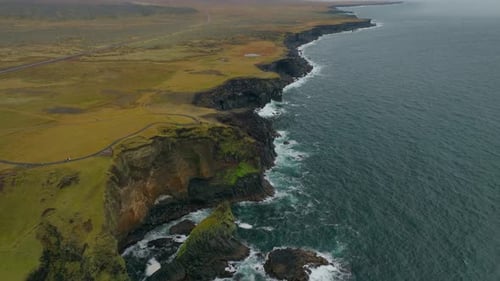 Aerial view of crispy waves breaking on the cliffs along the coast in Iceland.