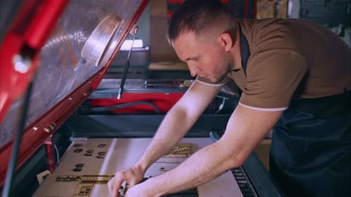 Techniker extrahiert lasergeschnittene Holzteile aus einer CNC-Maschine