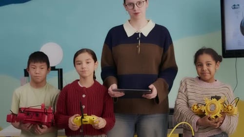 Portrait of Young Female Robotics Teacher with Diverse Pupils in Class