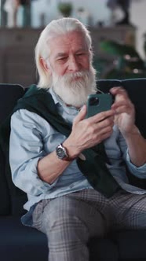 Senior Man Using Mobile Phone on Sofa