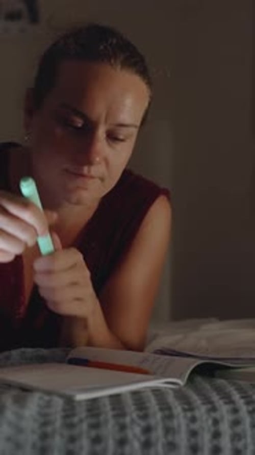 Woman Studying in Bed at Night with Phone