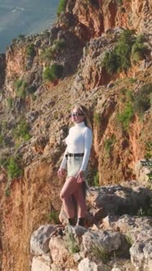 Vertical Video Beautiful Model Striking Poses on a Cliff Above the Mediterranean Waters