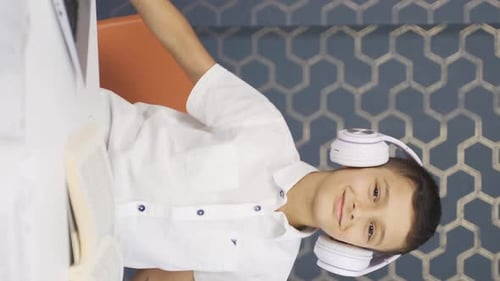 Smiling Boy Listens to Music While Studying