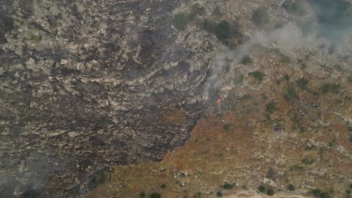 Wildfires burning mountainside and leaving scorched earth overhead shot