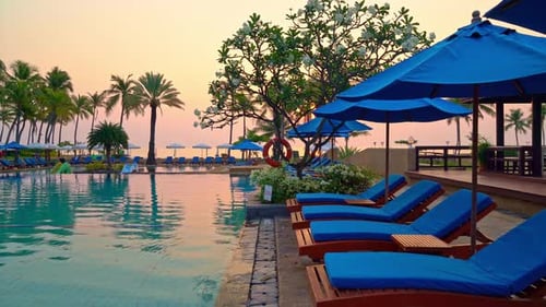 bed pool and umbrella around swimming pool with sunset or sunrise sky