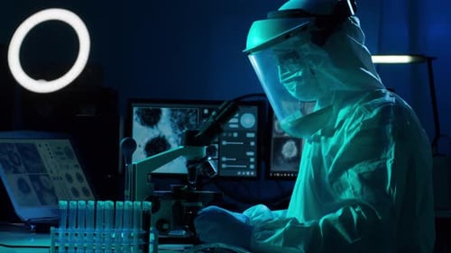 Scientist in Lab Analyzing Blood Under Microscope