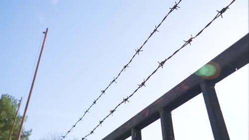 low angle view POV of wire fence above metal doors protective layer spikes two lines from entering p
