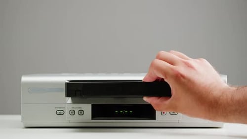 Hand Inserts VHS Tape into VCR