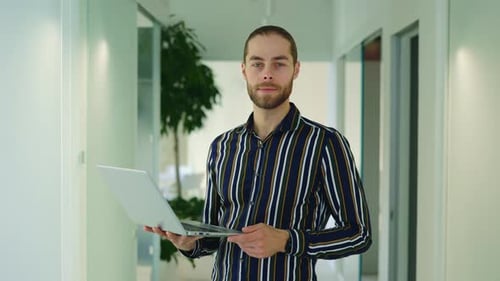 Portrait of Charismatic Handsome Businessman Using Laptop Standing in Office