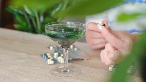 Person Holding Capsule With Glass of Green Liquid