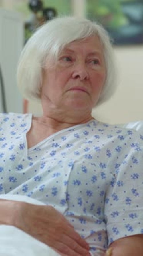 Senior Woman Receives Glass in Hospital Bed