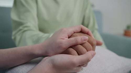 Close up hands of doctor touching senior patient’s hands reassuring