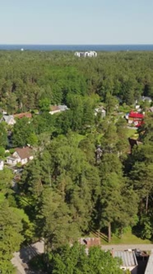 Vertical Drone Orbit Over Jurmala Forest and Residential Area with View Toward Baltic Sea, Latvia