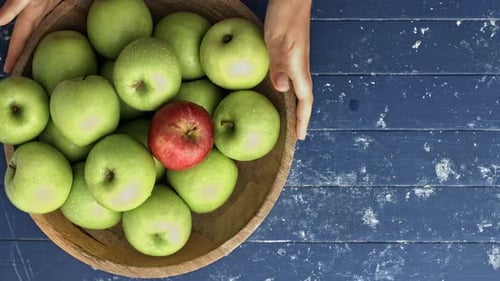 Overhead shot of green apples in wooden bowl