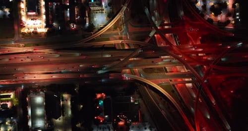 Busy multi-level interchange with red illumination at night.