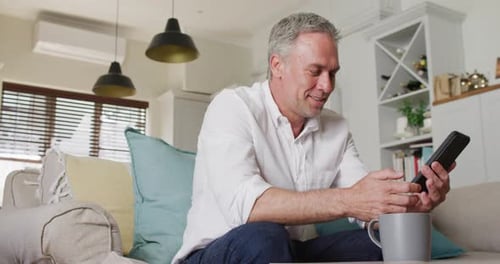 Adult Man Using Smartphone on Couch at Home