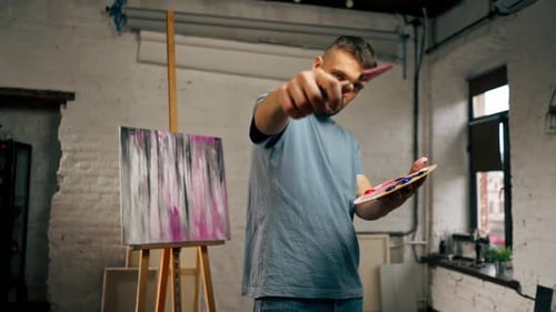 in an Art Studio an Artist Takes Measurements By Eye with Palette Knife Directly Into the Camera
