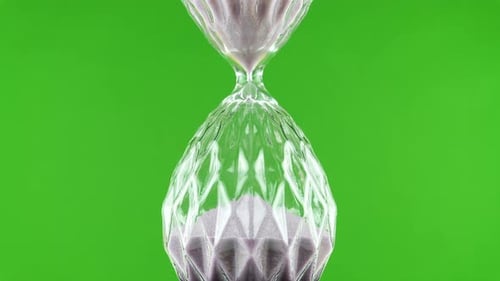Unusual Rotating Hourglass Flask On A Green Background.