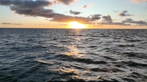 Flying low over ocean at sunrise. Aerial view of drone flight over sea in sunset. Camera files towar