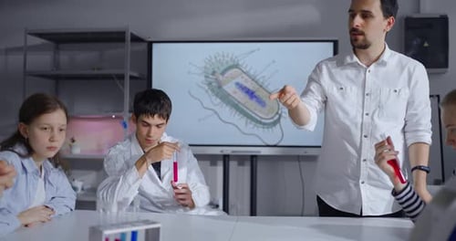 Teacher Man Speaking In Classroom Explaining To Young Student Of School About Chemistry And Biology