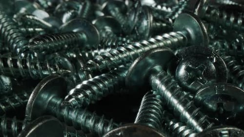 Un montón de tornillos de metal sobre un fondo negro, fondo de tornillos de metal de acero inoxidable