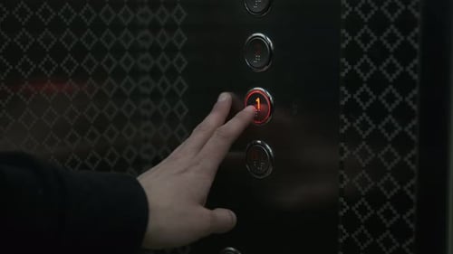 Die Hand des Mannes drückt die Aufzugstaste, um nach unten zu fahren