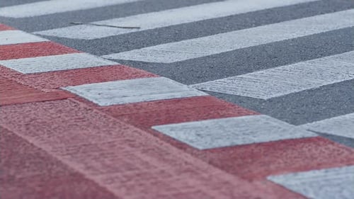 Cruzamento de pedestres de perto, listras brancas e ciclovia vermelha em estrada de asfalto