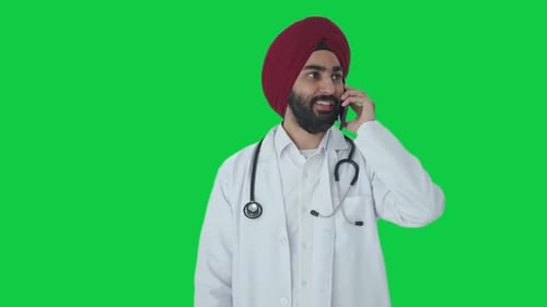 Happy Sikh Indian doctor talking on call Green screen