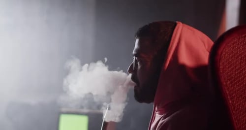 Man Relaxes Indoors Smoking Hookah and Drinking