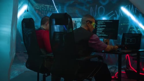 Two people working on computers in a dark room