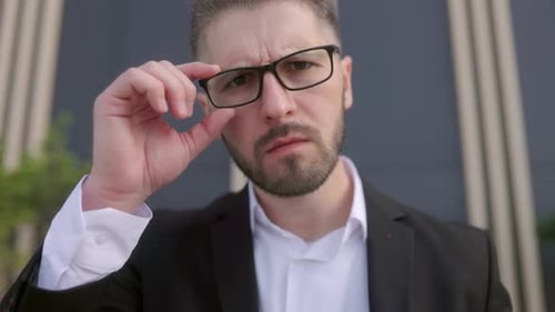 Man Adjusts Glasses Wearing a Suit Jacket