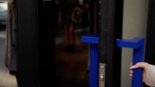 Woman Opens Door to Urban Building Entrance